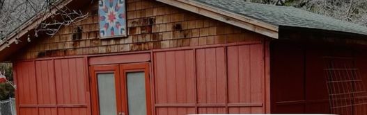 A red wooden barn with a painted quilt square above double doors